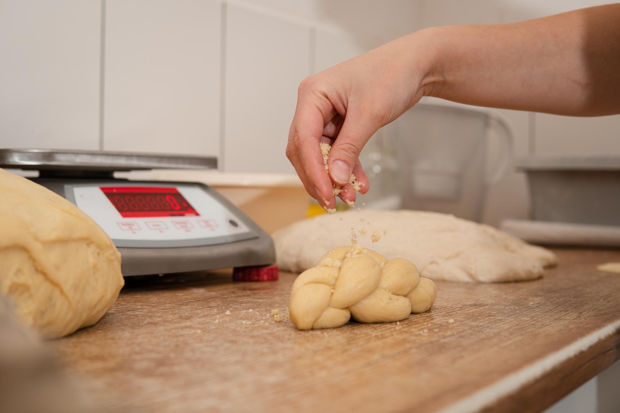 Close-up of hands kneading dough with digital scale
